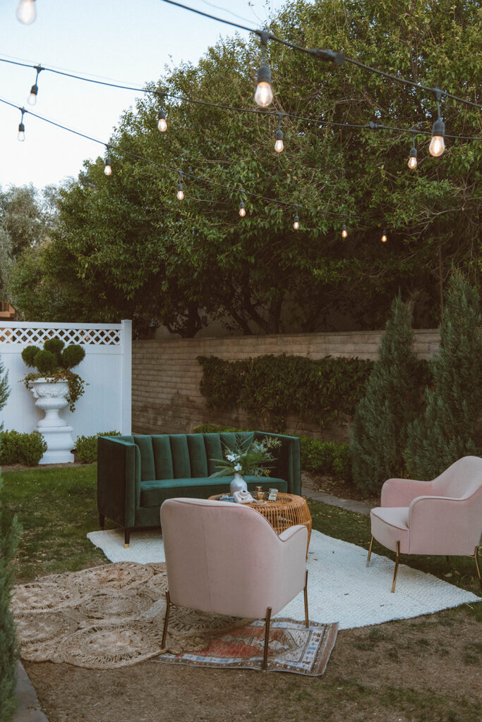 midcentury modern with a palm springs chic twist on cozy lounge. Two pink chairs, boho rugs and a large green couch outdoors