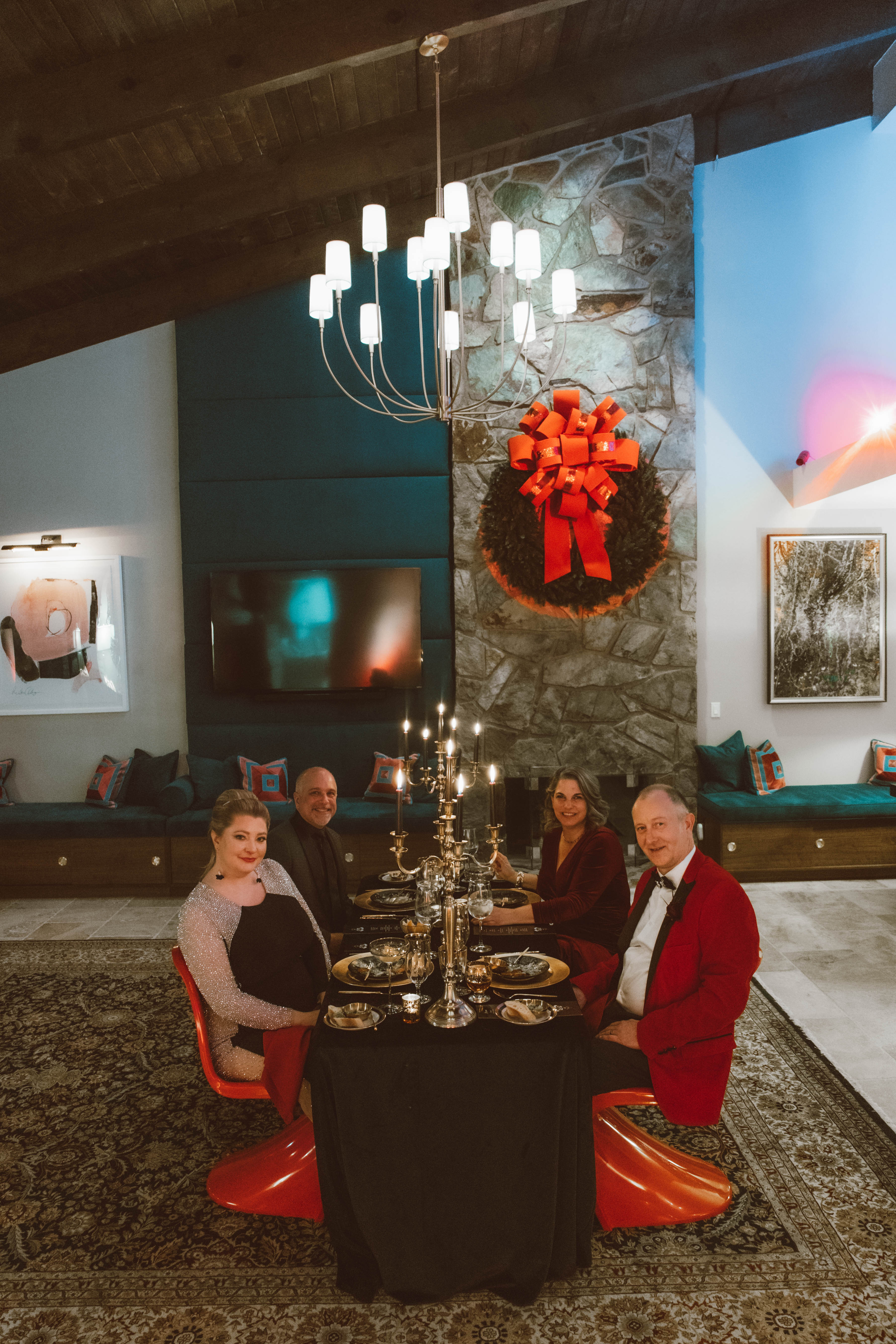 A photo of plated dinner with four guests at intimate las vegas elopement in december. Everything is christmas themed in gold, red, black.
